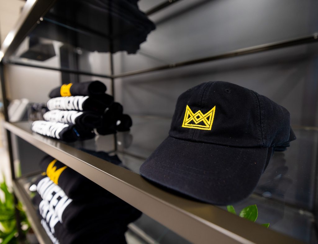 Black hat with gold crown sitting on glass shelf