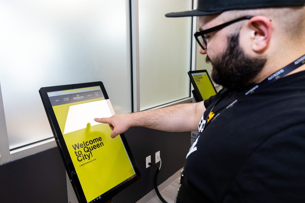 Queen City Dispensary staff member demonstrating how to use the in-store kiosks