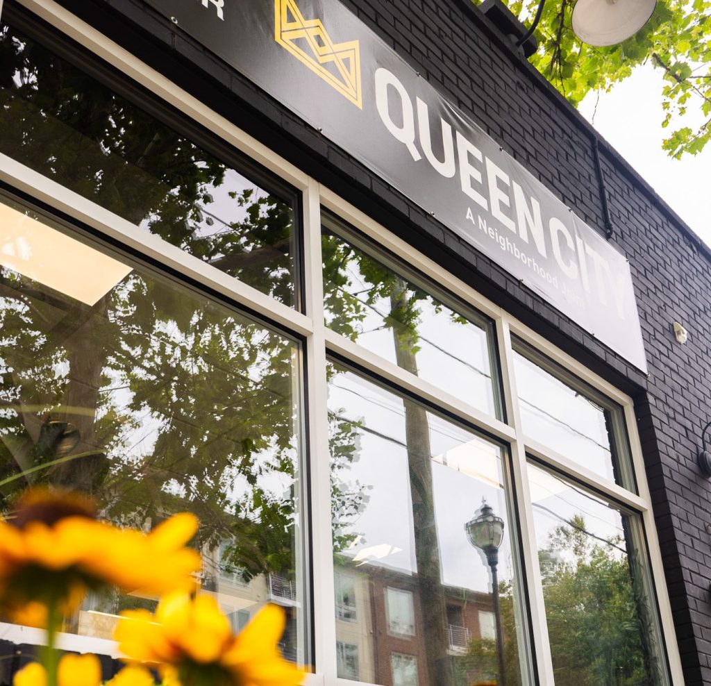 An image of Queen City Dispensary in Plainfield, NJ from the outside with blurred yellow sunflowers in the foreground.