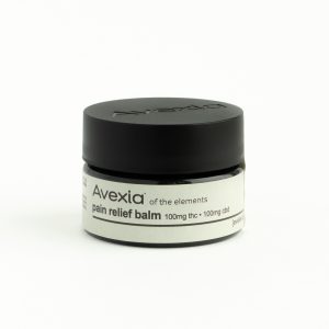 Avexia balm is pictured. The jar has a black lid and a cream colored label.