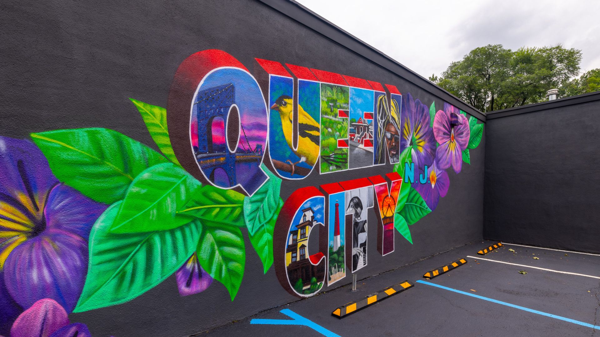 The Queen City mural uplifts local community in Plainfield, NJ. The words "Queen City" are spelled out against a black background. Each letter features a different aspect of New Jersey, Union County, and Plainfield.
