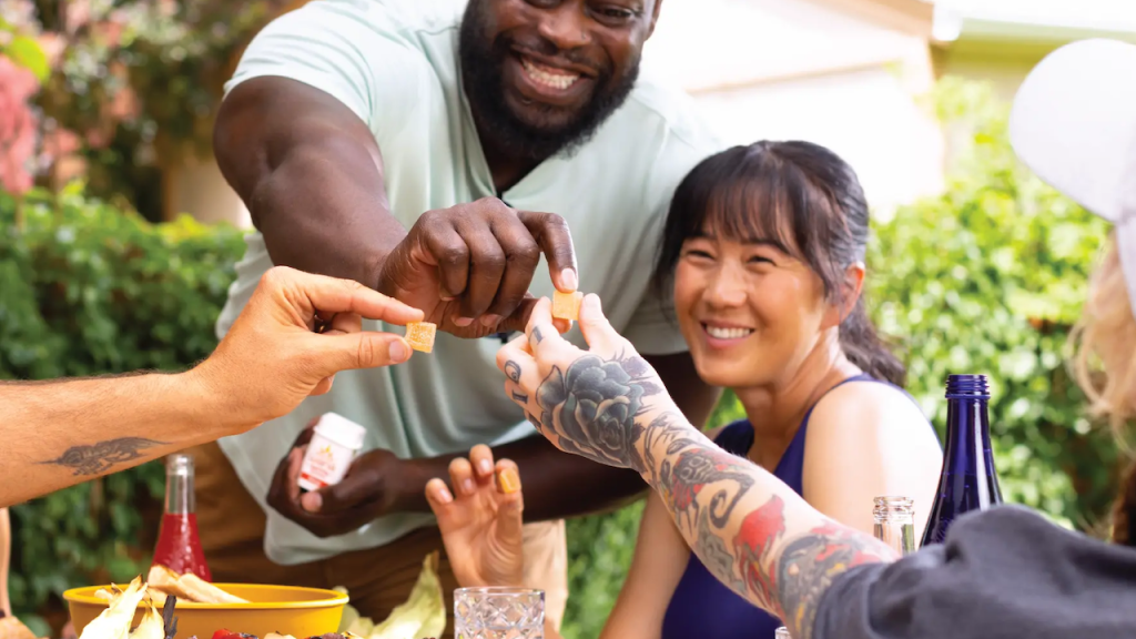 Group of happy people reaching for peach square weed gummies