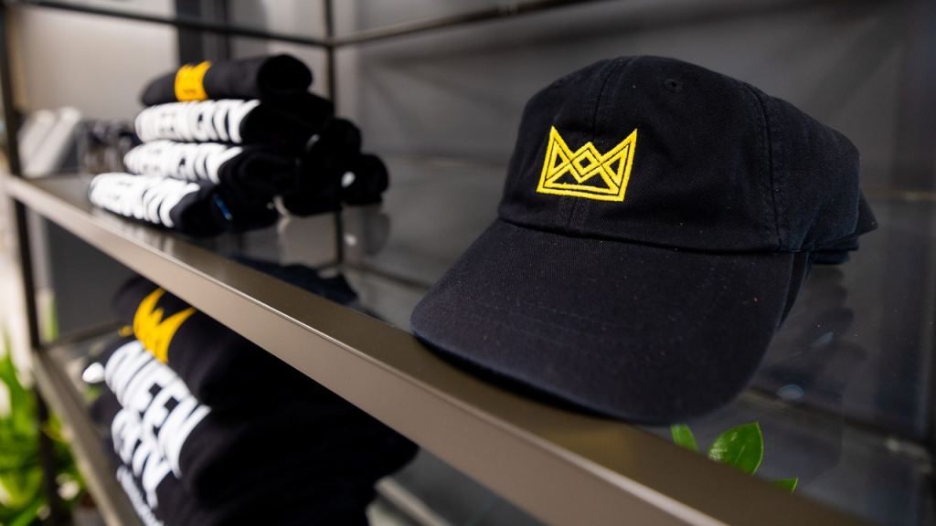 Black hat with gold crown sitting on glass shelf