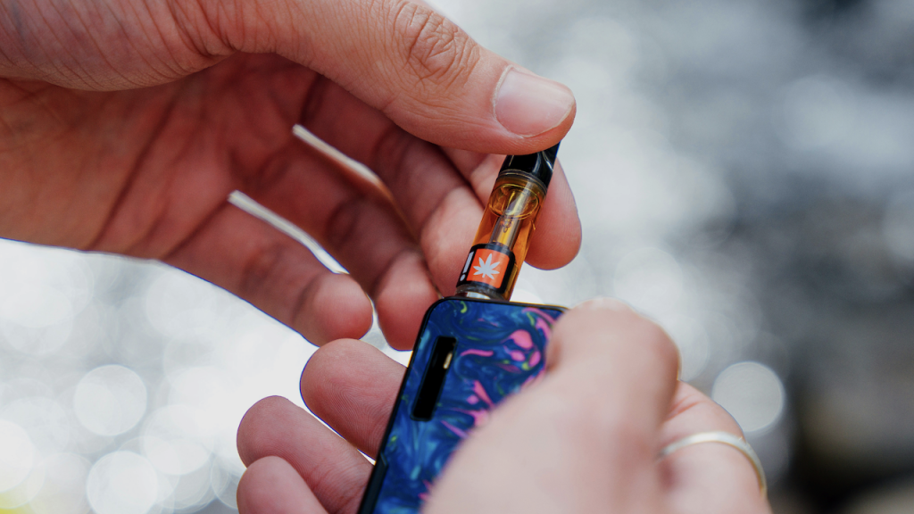 Up close of hands holding a THC vape battery and Cartridge.