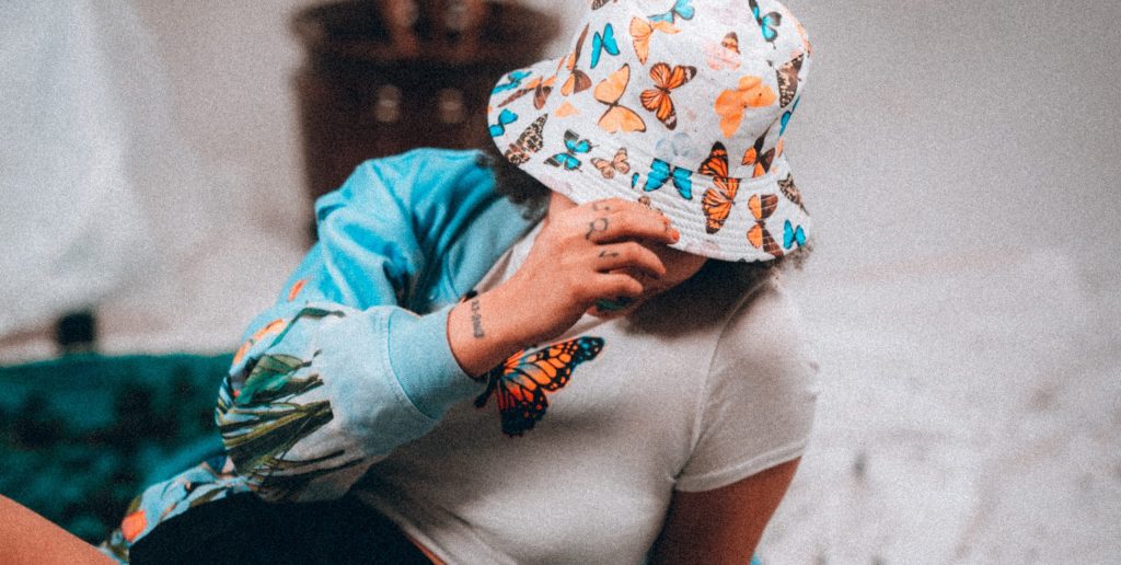 Person wearing bucket hat with butterflies and a butterfly t-shirt