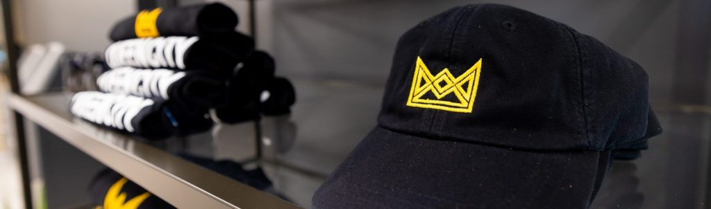 Black hat with gold crown sitting on glass shelf