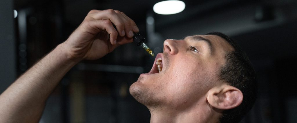 Person taking tincture in front of dark background