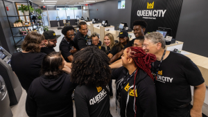 Queen City team huddling together in unity inside their Plainfield dispensary, celebrating a year of community impact and connection.